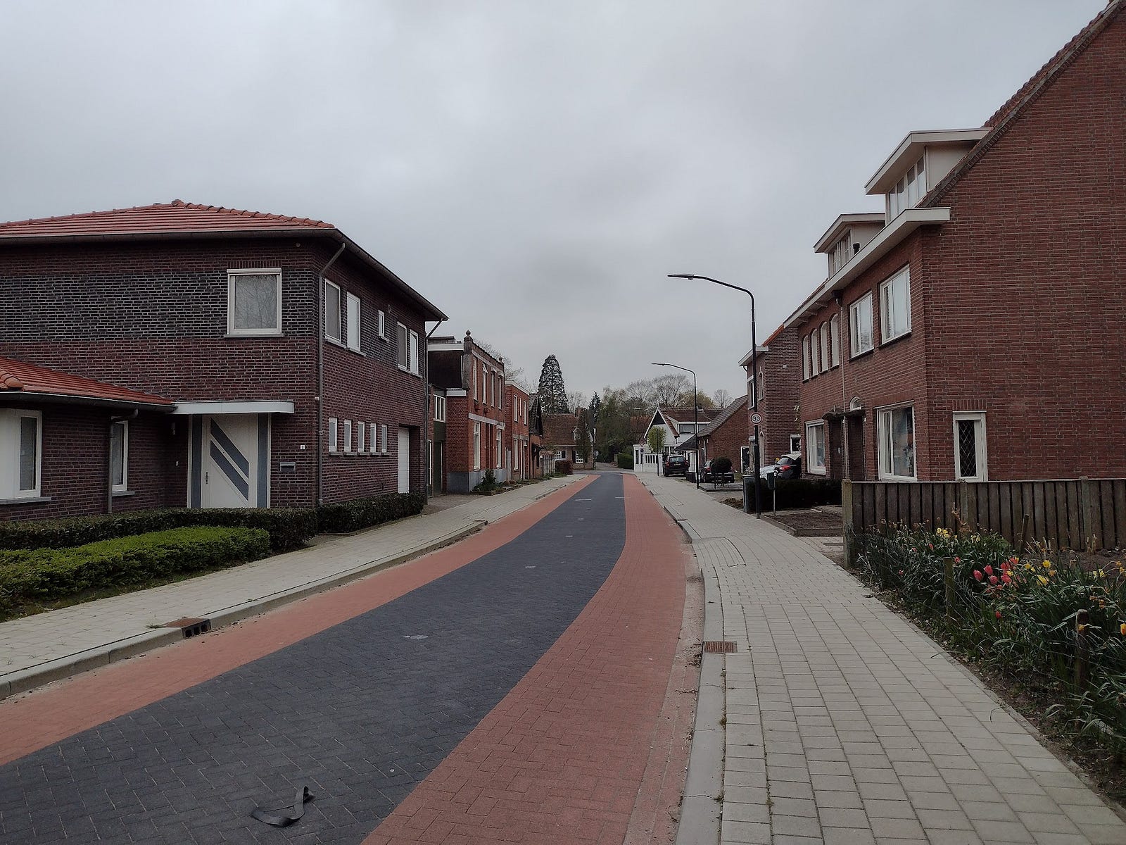 An ordinary residential street with red brick on the left and right edges